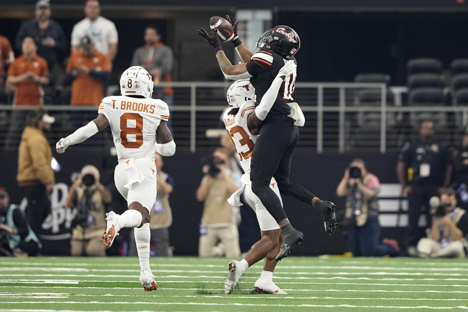Oklahoma State wide receiver Rashod Owens (10) leaps to make a catch on a long pass over Texas defensive backs Jahdae Barron (23) and Terrance Brooks (8) in the first half of the Big 12 Conference championship NCAA college football game in Arlington, Texas, Saturday, Dec. 2, 2023. (AP Photo/Tony Gutierrez)