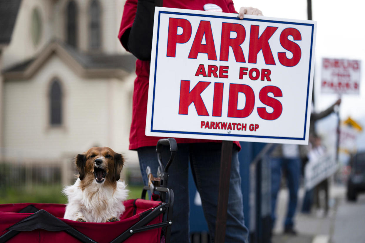 A protestor holds a sign that reads 'PARKS ARE FOR KIDS.' (Jenny Kane / AP)