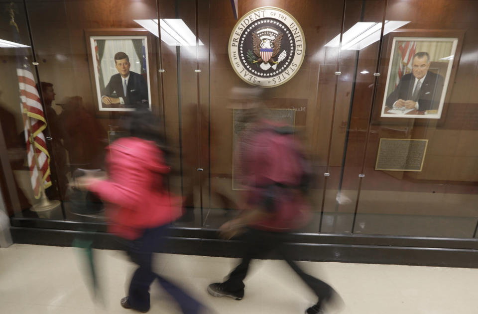 In this photo made Thursday, Nov. 7, 2013, hospital workers walk down hallway featuring a display that includes portraits of John F. Kennedy and Lyndon B. Johnson and the presidential seal at Parkland Memorial Hospital in Dallas. (AP Photo/LM Otero)