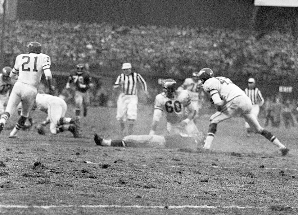 FILE - In this Nov. 21, 1960, file photo, New York Giants' Frank Gifford lies on field as play continues after he was knocked unconscious by Philadelphia Eagles' Chuck Bednarik (60) as Gifford was carrying the ball in the fourth quarter of a football game at New York's Yankee Stadium. The NFL revealed 70 of the 100 greatest plays in league history on Friday night with a TV special produced by NFL Films that has everything from spectacular offensive performances to defensive gems. In balloting conducted by The Associated Press, 68 media members on a nationwide panel voted for their top 100. Among those disclosed is the brutal hit applied by Bednarik on Gifford in 1960. (AP Photo/File)