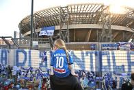 A girl sits on a man's shoulders as she looks at gadgets and memorabilia commemorating soccer legend Diego Maradona outside the San Paolo stadium, in Naples, southern Italy, Thursday, Nov. 26, 2020. Maradona died Wednesday, Nov. 25, 2020 in Buenos Aires. (AP Photo/Alessandra Tarantino)