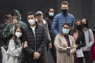 People wear face masks as they watch a street performer in Montreal, Saturday, Oct. 24, 2020, as the coronavirus pandemic continues. (Graham Hughes/The Canadian Press via AP)