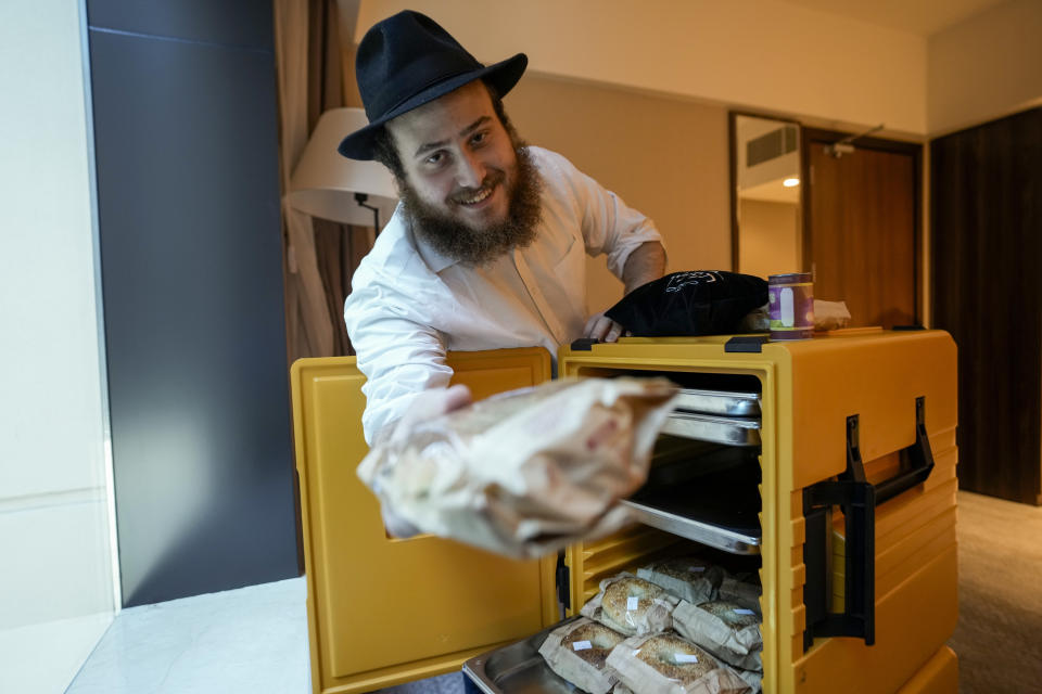 Eli Chitrik from Turkey shows bagel sandwiches at his hotel room in Doha, Qatar, Monday, Nov. 28, 2022. Stored into bright orange cases in Rabbi Eli Chitrik’s hotel room are bagels stuffed with vegetables. The labels declare the sandwiches kosher, or in compliance with Judaism’s set of dietary regulations. Freshly baked, they are made in Qatar at a designated kitchen, set up to feed Jewish World Cup visitors who want to keep kosher during the tournament. (AP Photo/Moises Castillo)