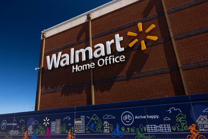 The image shows the exterior of the Walmart Home Office building with the Walmart logo prominently displayed. A mural below shows various illustrations and the text 