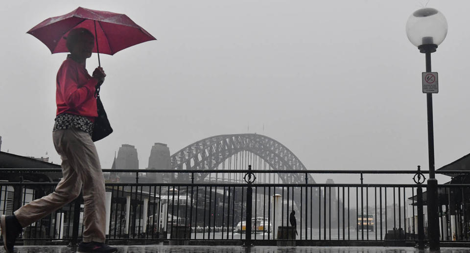 A person walking with an umbrella in Sydney while it storms across the East Coast of Australia.