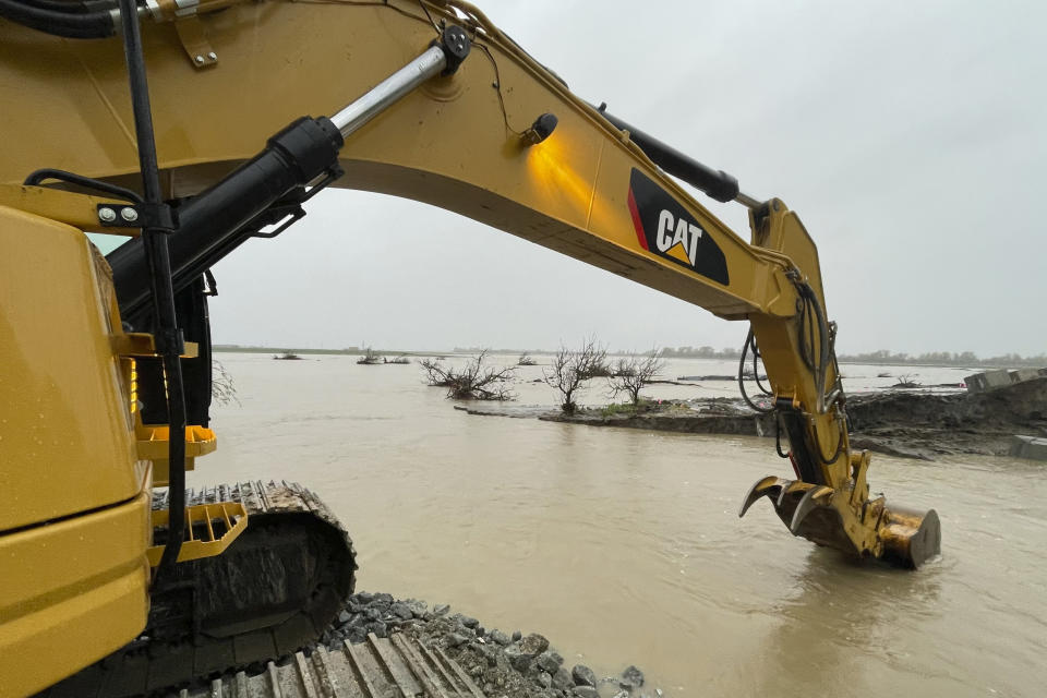 A crew uses heavy machinery to repair a levee rupture at the Pajaro River in Monterey County, Calif., Tuesday, March 14, 2023. Forecasters warned of more flooding, potentially damaging winds and difficult travel conditions on mountain highways as a new atmospheric river pushed into swamped California early Tuesday. (AP Photo/Haven Daley)