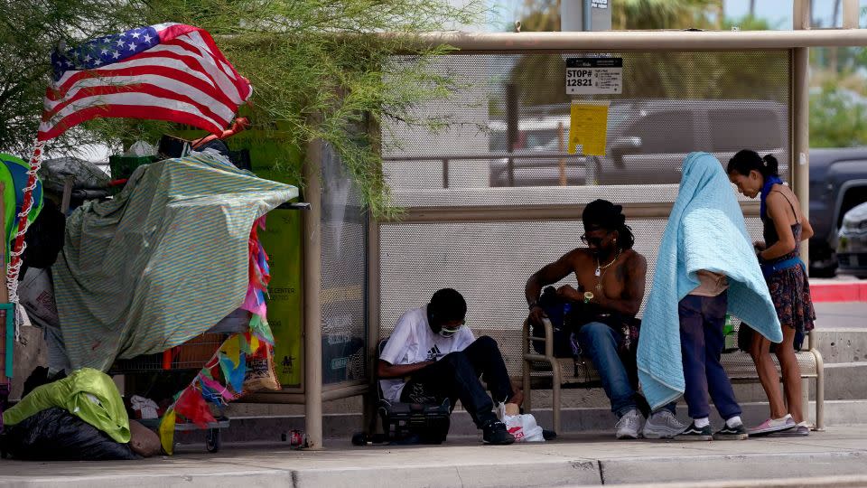 People gather under the shade of a Phoenix bus stop, Tuesday, July 11, 2023. Even desert residents accustomed to scorching summers are feeling the grip of an extreme heat wave smacking the Southwest this week.  - Matt York/AP