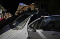 Haitian Carlo Richard, whose Chilean identity card expired and has been rejected for renewal, repairs a car outside his home in the Dignidad camp in Santiago, Chile, Thursday, Sept. 30, 2021. “What can I do? I can’t do anything, (just) hold on until there is a change in our country so that we can return,” he said, referring to returning Haiti. (AP Photo/Esteban Felix)
