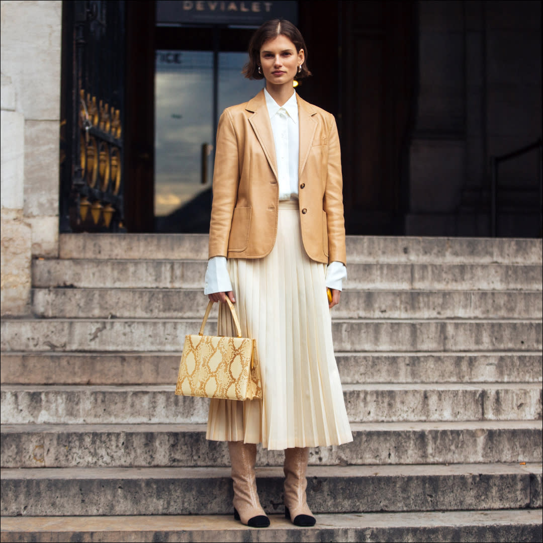  woman in white pleated skirt, blazer, and boots 