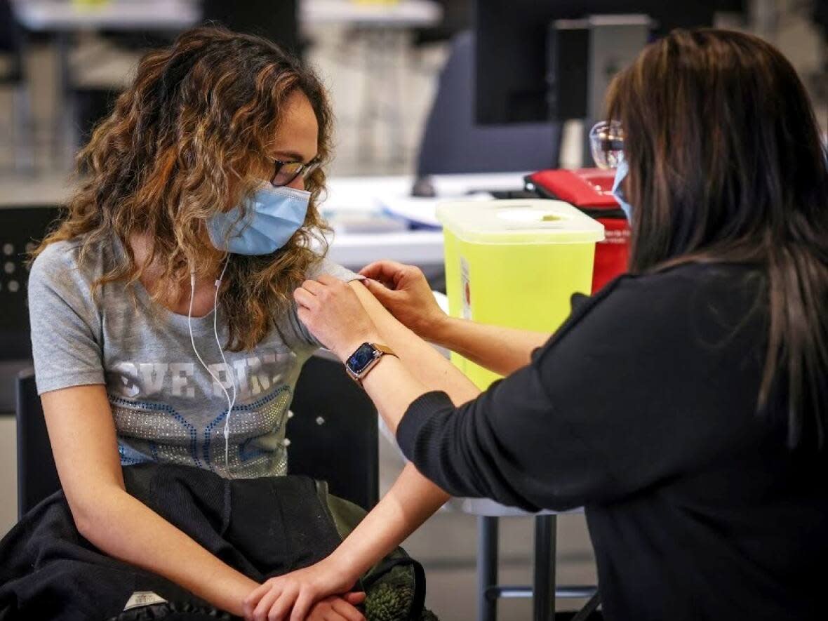 People across the world are getting their COVID-19 vaccinations, like this person at a clinic in Calgary. Some, however, remain hesitant. (Leah Hennel/AHS - image credit)