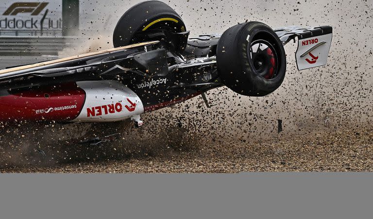 El automóvil volcado del piloto chino de Alfa Romeo, Zhou Guanyu, se desliza a través de la grava después de un accidente al comienzo del Gran Premio Británico de Fórmula Uno en el circuito de carreras de Silverstone en Silverstone, Inglaterra central, el 3 de julio de 2022. (Foto de Ben Stansall / AFP)