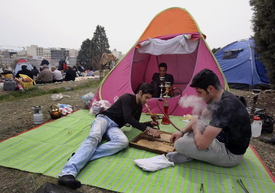 Iranian men play backgammon while smoking water pipes as they spend time outdoors observing the ancient festival of Sizdeh Bedar, an annual public picnic day on the 13th day of the Iranian new year, at Pardisan Park, in Tehran, Iran, Wednesday, April 2, 2014. Sizdeh Bedar, which comes from the Farsi words for “thirteen” and “day out,” is a legacy from Iran’s pre-Islamic past that hard-liners in the Islamic Republic never managed to erase from calendars. Many say it’s bad luck to stay indoors for the holiday. (AP Photo/Vahid Salemi)