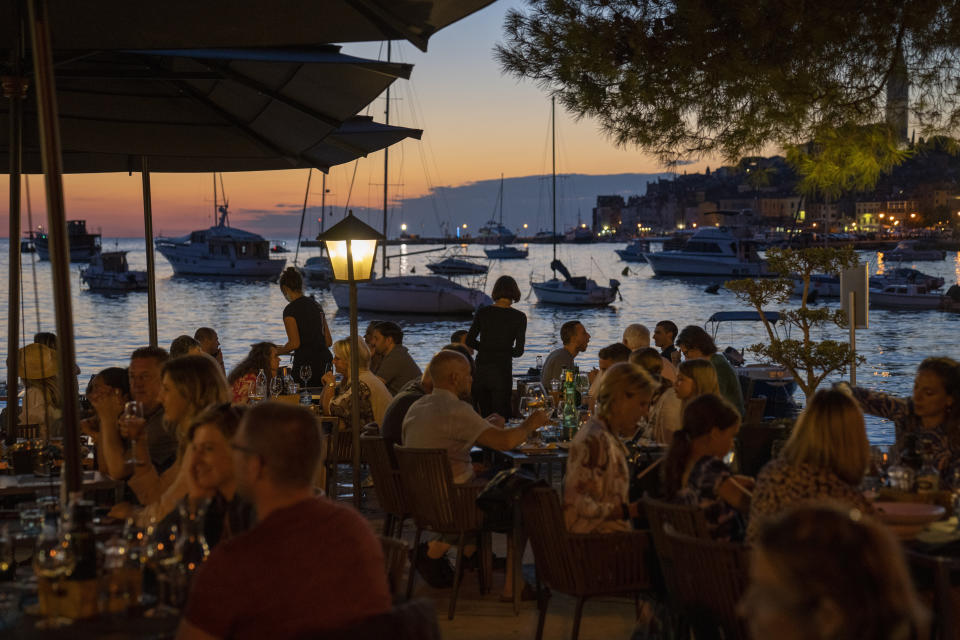 Holidaymakers sit in a seafront restaurant, in the Adriatic town of Rovinj, Croatia, Friday, Aug. 27, 2021. Summer tourism has exceeded even the most optimistic expectations in Croatia this year. Beaches along the country's Adriatic Sea coastline are swarming with people. Guided tours are fully booked, restaurants are packed and sailboats were chartered well in advance. (AP Photo/Darko Bandic)