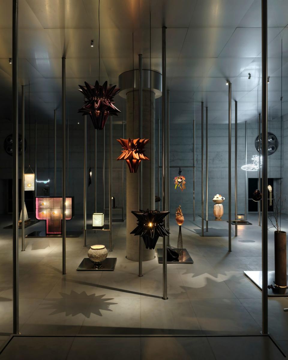 a glass display case with a few candles and a couple of gold and red flowers