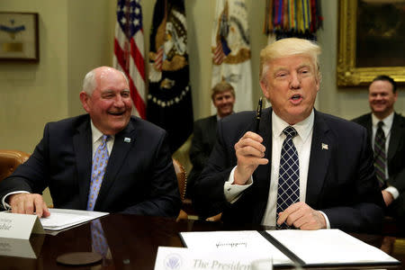 U.S. President Donald Trump holds a pen after signing an executive order next to Secretary of Agriculture Sonny Perdue during a roundtable discussion with farmers at the White House in Washington, U.S. April 25, 2017. REUTERS/Yuri Gripas