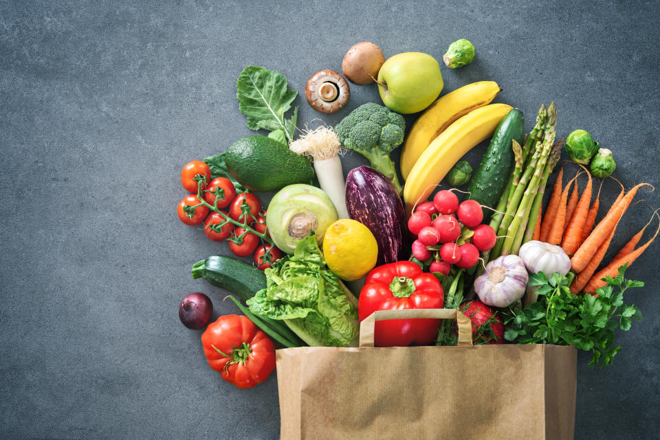 Healthy food selection. Shopping bag full of fresh vegetables and fruits. Flat lay food on table