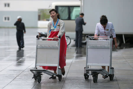 Staff push trolleys in the rain outside the international airport in Pyongyang, North Korea May 3, 2016. REUTERS/Damir Sagolj