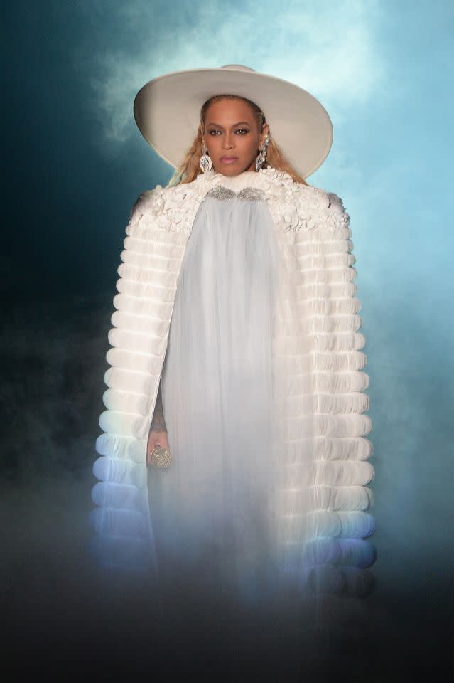 Beyoncé in einem weißen bodenlangen Cape und Hut mit weiter Krempe