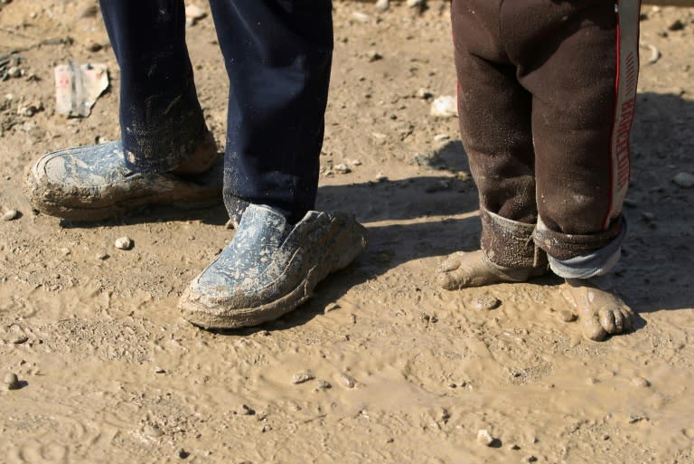 Displaced Iraqi children from Mosul walk in the mud towards refugee camps on March 24, 2017