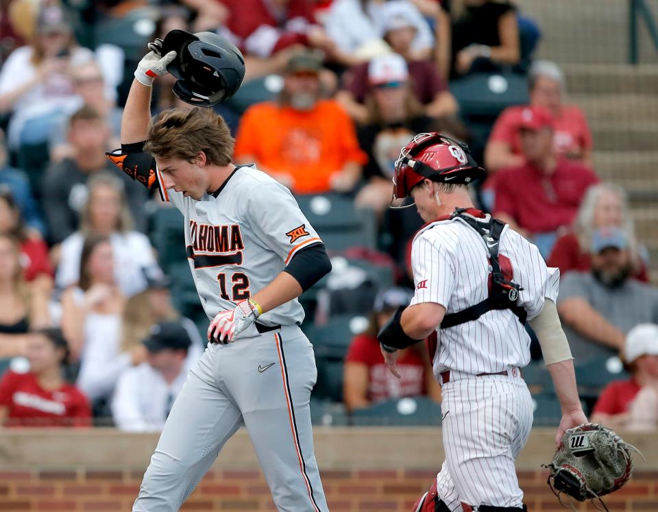 OSU's Colin Brueggemann (12) reacts after grand slam next to OU's Easton Carmichael (2) in the third inning of a 13-2 win Thursday night at L. Dale Mitchell Park in Norman.