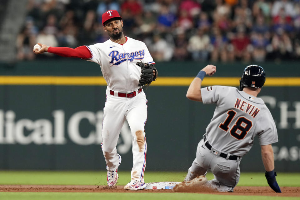 Texas Rangers second baseman Marcus Semien, left, throws turning a double play against Detroit Tigers' Tyler Nevin (18) with Jake Marisnick out at first base during the second inning of a baseball game in Arlington, Texas, Tuesday, June 27, 2023. (AP Photo/LM Otero)