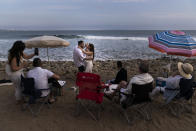 Pejiman Sabet and his wife, Gili, dance in front of their family members on Topanga Beach in Malibu, Calif., Tuesday, Sept. 28, 2021, as a surfer rides a wave in the distance. The couple, who were fully vaccinated, said the gathering was just to appreciate life. "Love is everything right now," said the wife. (AP Photo/Jae C. Hong)