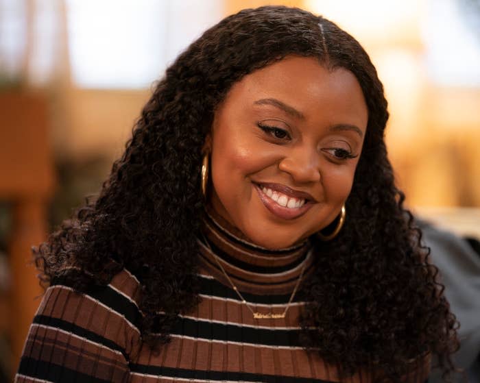 Woman smiling in a striped turtleneck top, wearing hoop earrings