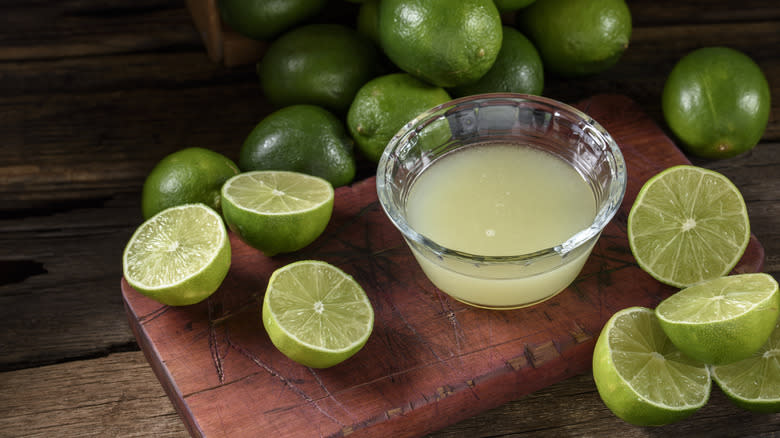 Lime juice in a small glass bowl surrounded by limes