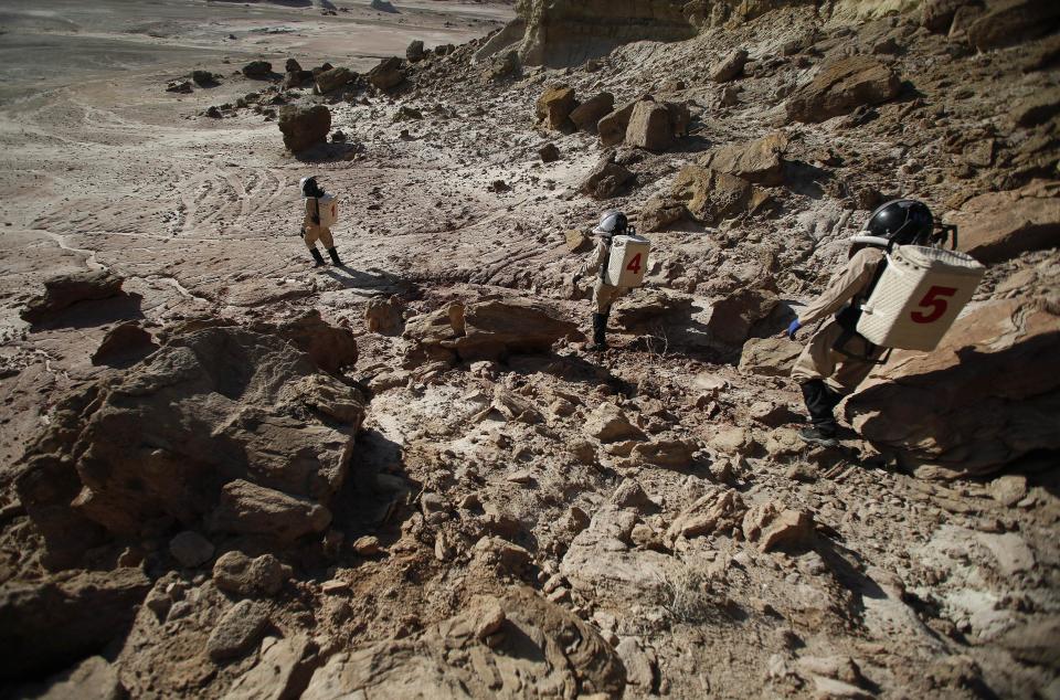 Members of Crew 125 EuroMoonMars B mission venture out in their simulated spacesuits to collect geologic samples for study at the Mars Desert Research Station (MDRS) in the Utah desert March 2, 2013. The MDRS aims to investigate the feasibility of a human exploration of Mars and uses the Utah desert's Mars-like terrain to simulate working conditions on the red planet. Scientists, students and enthusiasts work together developing field tactics and studying the terrain. All outdoor exploration is done wearing simulated spacesuits and carrying air supply packs and crews live together in a small communication base with limited amounts of electricity, food, oxygen and water. Everything needed to survive must be produced, fixed and replaced on site. Picture taken March 2, 2013. REUTERS/Jim Urquhart