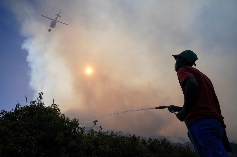 A man and a helicopter pour water to put out a fire.