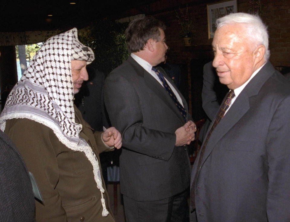 FILE - In this Oct. 21, 1998 file photo, Israeli Foreign Minister Ariel Sharon, right, stands near but does not look at, or shake hands with, Palestinian leader Yasser Arafat at Wye Plantation, Maryland. Before becoming a candidate, Sharon proudly boasted he had never shaken hands with Arafat, and called the Palestinian leader a "murderer and a liar" in an interview with the New Yorker magazine. Sharon, the hard-charging Israeli general and prime minister who was admired and hated for his battlefield exploits and ambitions to reshape the Middle East, died Saturday, Jan. 11, 2014. The 85-year-old Sharon had been in a coma since a debilitating stroke eight years ago. (AP Photo/Israel Government Press Office, File)