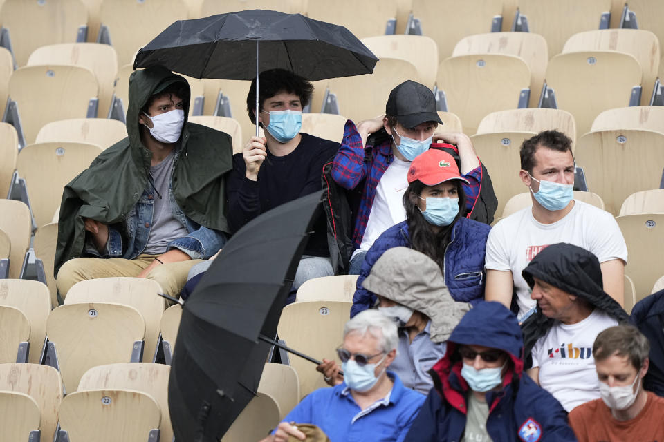 Spectators on the Simonne Mathieu court put up umbrellas as rain falls while they watch Japan's Kei Nishikori play against Switzerland's Henri Laakosonen during their third round match on day 6, of the French Open tennis tournament at Roland Garros in Paris, France, Friday, June 4, 2021. (AP Photo/Michel Euler)