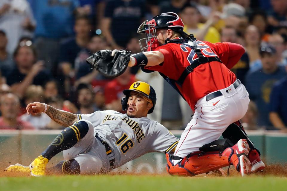 The Brewers' Kolten Wong slides safely across the plate as the throw home gets past Red Sox catcher Kevin Plawecki during the ninth inning Friday night.