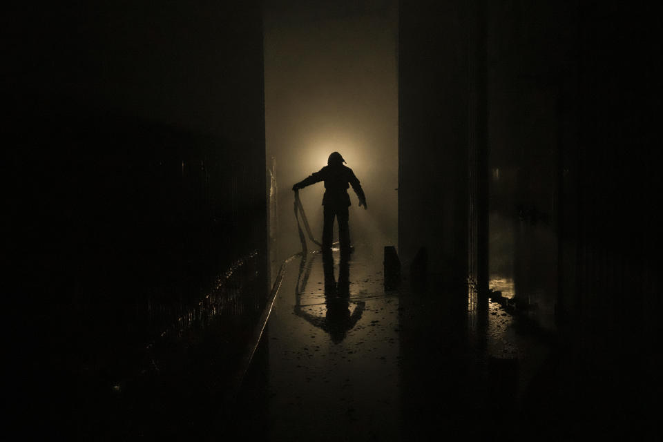 A Ukrainian firefighter drags a hose inside a large food products storage facility which was destroyed by an airstrike in the early morning hours in Brovary, north of Kyiv, Ukraine, Sunday, March 13, 2022. Waves of Russian missiles pounded a military training base close to Ukraine's western border with NATO member Poland, killing 35 people, following Russian threats to target foreign weapon shipments that are helping Ukrainian fighters defend their country against Russia's grinding invasion.(AP Photo/Vadim Ghirda)