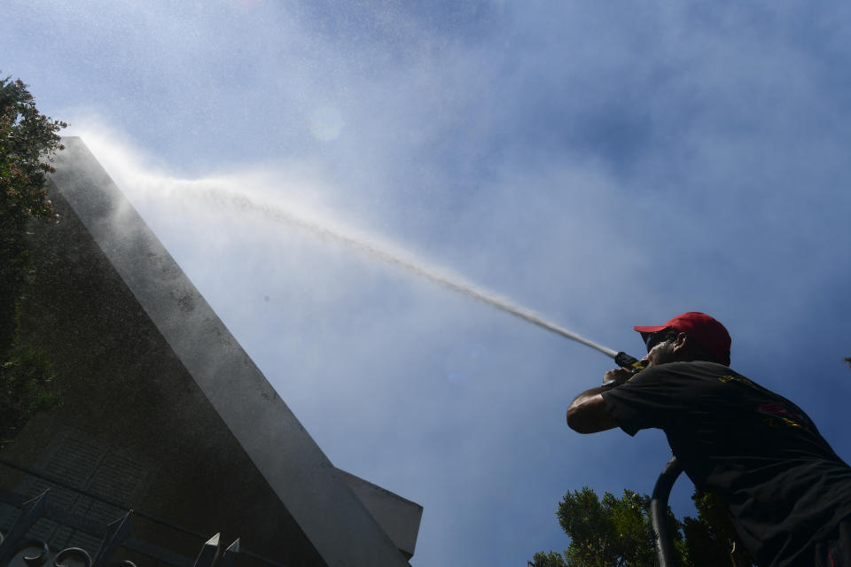 A firefighter tries to extinguish burning embers on a house, in Thrakomacedones area, in northen Athens, Greece, Saturday, Aug. 7, 2021. Wildfires rampaged through massive swathes of Greece's last remaining forests for yet another day Saturday, encroaching on inhabited areas and burning scores of homes, businesses and farmland. (AP Photo/Michael Varaklas)