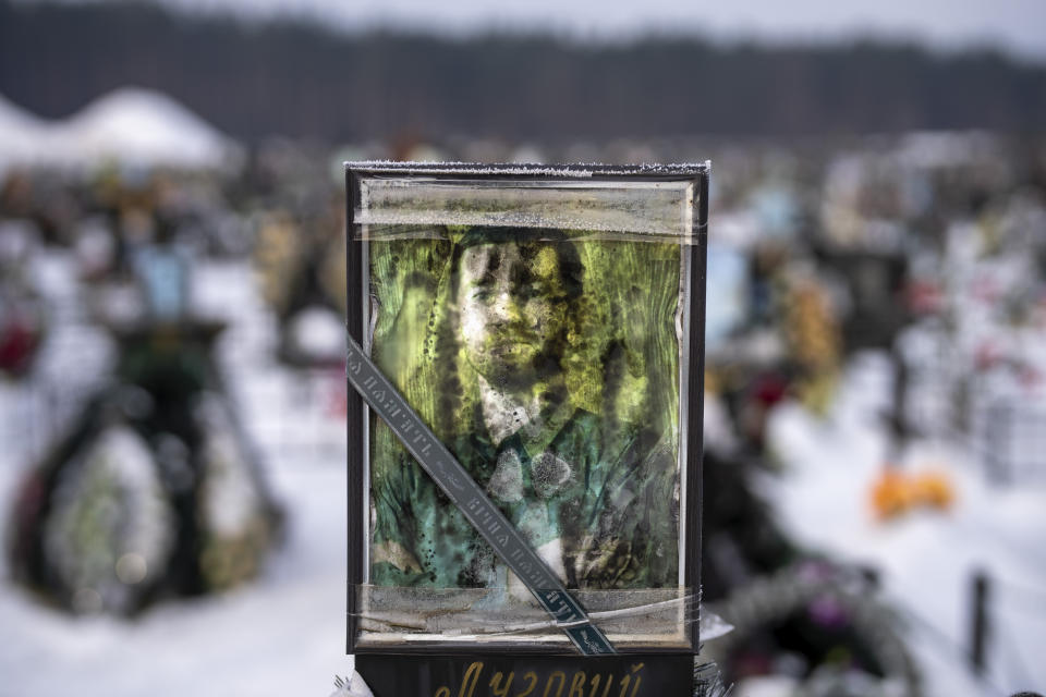 A worn-out portrait of Ivan Oleksandr Volodymyrovych, 41, sits on his grave at a cemetery in Irpin, Ukraine, on the outskirts of Kyiv, on Thursday, Feb. 9, 2023. He was killed on March 5, 2022. (AP Photo/Emilio Morenatti)