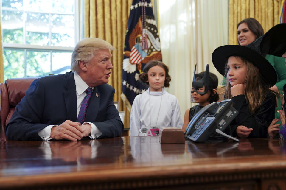 President Donald Trump talks with from lwft, Natalynn Parkinson, 6, Yume Inone, 6, and Phoebe Trabb, 7, who are dressed in their halloween costumes, Friday, Oct. 27, 2017. (AP Photo/Pablo Martinez Monsivais)