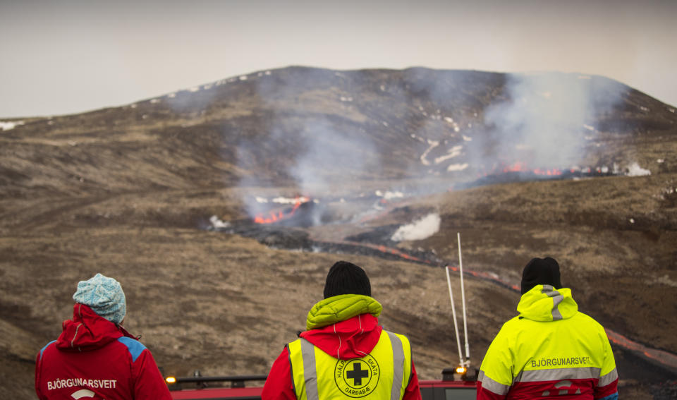 Members of the Search and Rescue Team, Bjorgunasveit look at a new fissure on a volcano on the Reykjanes Peninsula in southwestern Iceland, Monday, April 5, 2021. The new fissure has opened up at the Icelandic volcano that began erupting last month, prompting the evacuation of hundreds of hikers who had come to see the spectacle. Officials say the new fissure is about 500 meters (550 yards) long and about one kilometer (around a half-mile) from the original eruption site in the Geldinga Valley (AP Photo/Marco Di Marco)