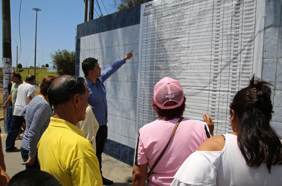 Voters look at a list indicating their voting stations during a referendum aimed at curbing corruption in Lima, Peru, Sunday, Dec. 9, 2018. The four questions on the ballot include measures that would prohibit legislators from immediate reelection, create stricter campaign finance rules and reform a scandal-tainted council charged with selecting judges (AP Photo/Cesar Olmos)