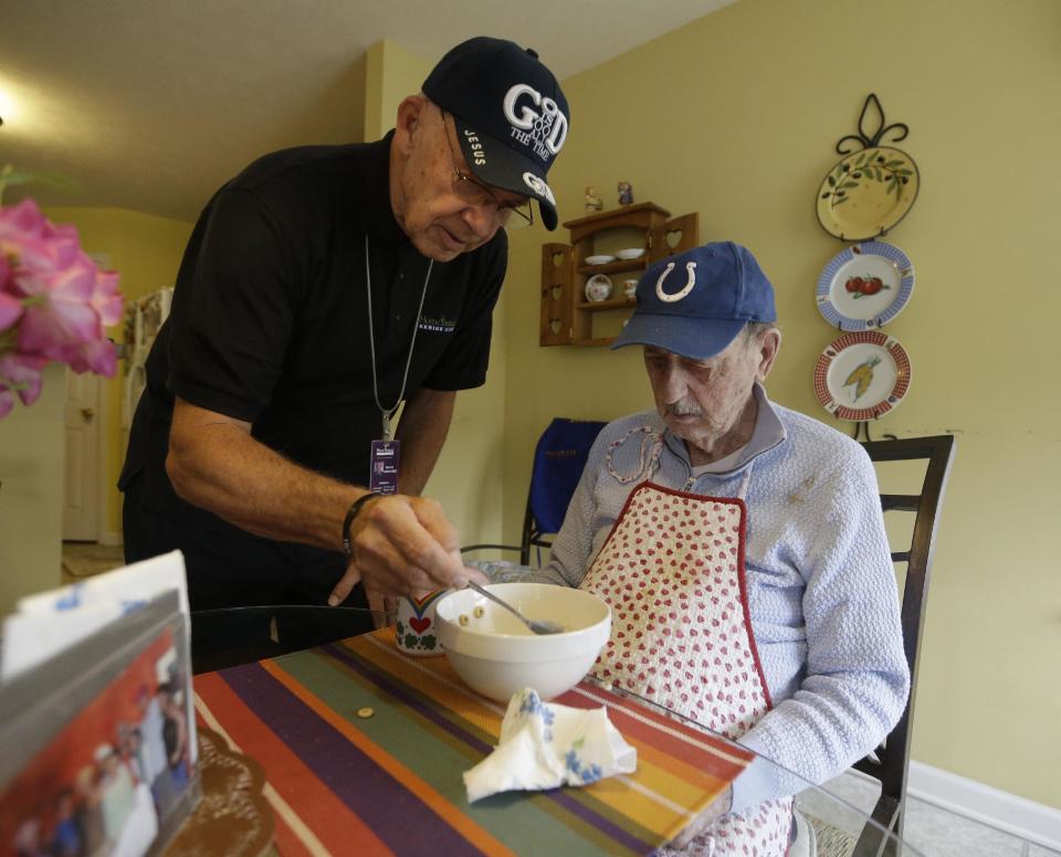 In this Nov. 21, 2103 photo, caregiver Warren Manchess, 74, left, helps Paul Gregoline, 92, with a meal, in Noblesville Ind. Burgeoning demand for senior services like home health aides is being met by a surprising segment of the workforce: Other seniors. Twenty-nine percent of so-called direct-care workers are projected to be 55 or older by 2018 and in some segments of that population older workers are the single largest age demographic. With high rates of turnover, home care agencies have shown a willingness to hire older people new to the field who have found a tough job market as they try to supplement their retirement income. (AP Photo/Darron Cummings)