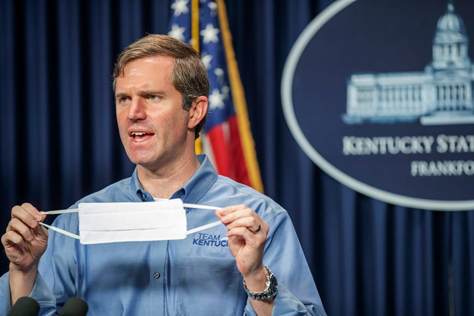 Kentucky Gov. Andy Beshear holds up a face mask while speaking about the novel coronavirus during a news conference at the state Capitol in Frankfort, Kentucky, April 26, 2020.