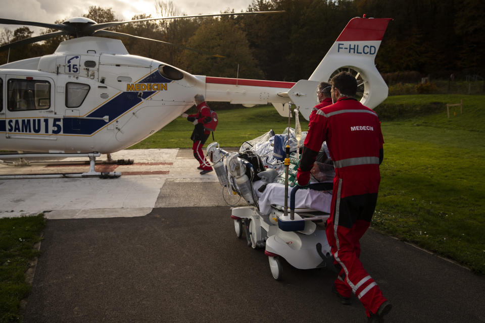 Medical personnel wheel a coronavirus patient on a bed as they prepare to transfer the patient by helicopter from the COVID-19 intensive care unit of the CHU Liege hospital to another hospital in Germany, in Liege, Belgium, Tuesday, Nov. 3 , 2020. (AP Photo/Francisco Seco)