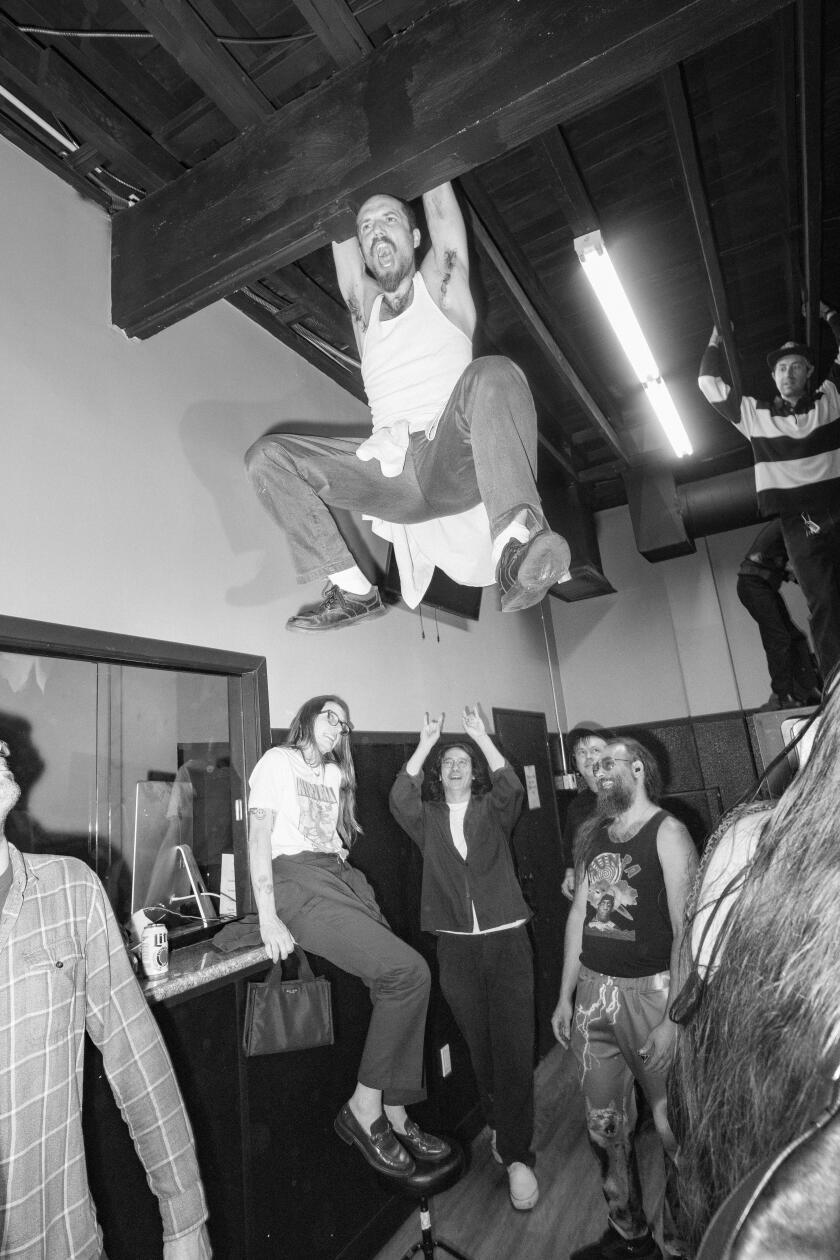 People watch as a person swings from the rafters at Laundry Wand.