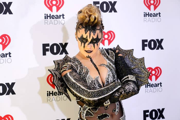 Person in dramatic makeup and spiked shoulder outfit on the red carpet