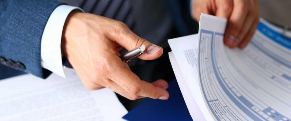 Male arm in suit flips through pile of insurance forms.