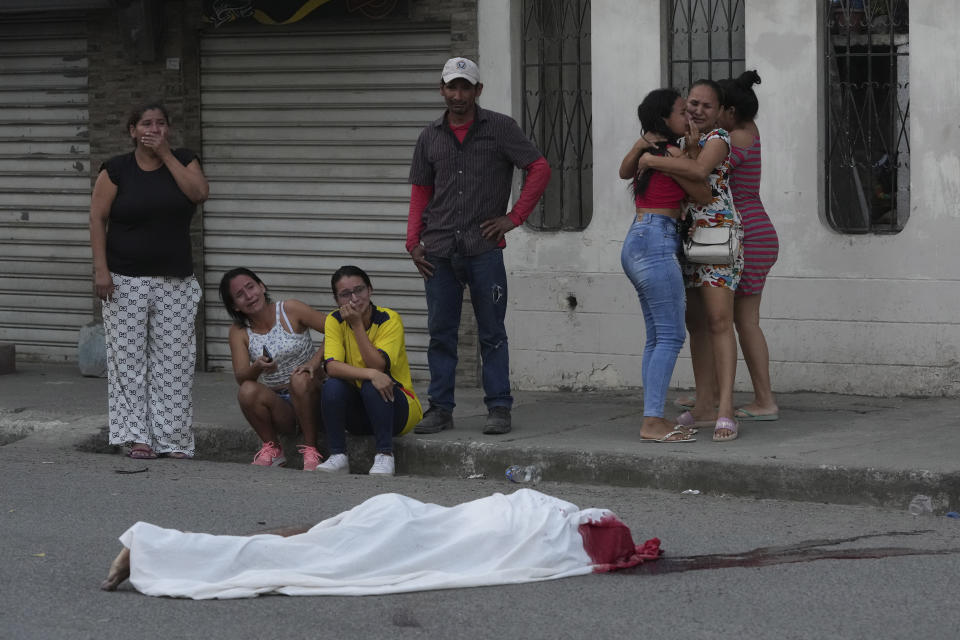 FILE - Persons grieve near the body of a man, killed in unknown circumstances, on a street in Duran Guayaquil, Ecuador, July 21, 2023. The country’s National Police tallied over 3,000 violent deaths in the first six months of this 2023, far more than the 2,042 reported during the same period in 2022. (AP Photo/Dolores Ochoa, File)