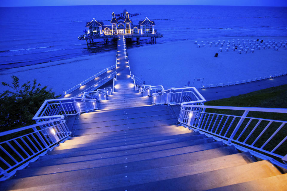 In this Friday May 22, 2020 photo, a restaurant a illuminated on a pier in Sellin on the island Ruegen, Germany. Germany's states, which determine their own coronavirus-related restrictions, have begun loosening lockdown rules to allow domestic tourists to return. ( Jens Buettner/dpa via AP)