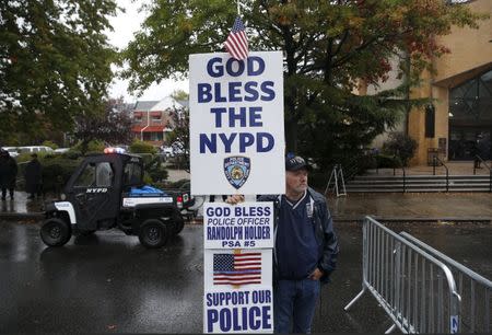 A man stands with a sign near the Greater Allen A.M.E. Cathedral of New York ahead of the funeral service for slain New York City Police (NYPD) officer Randolph Holder in the Queens borough of New York City, October 28, 2015. REUTERS/Shannon Stapleton