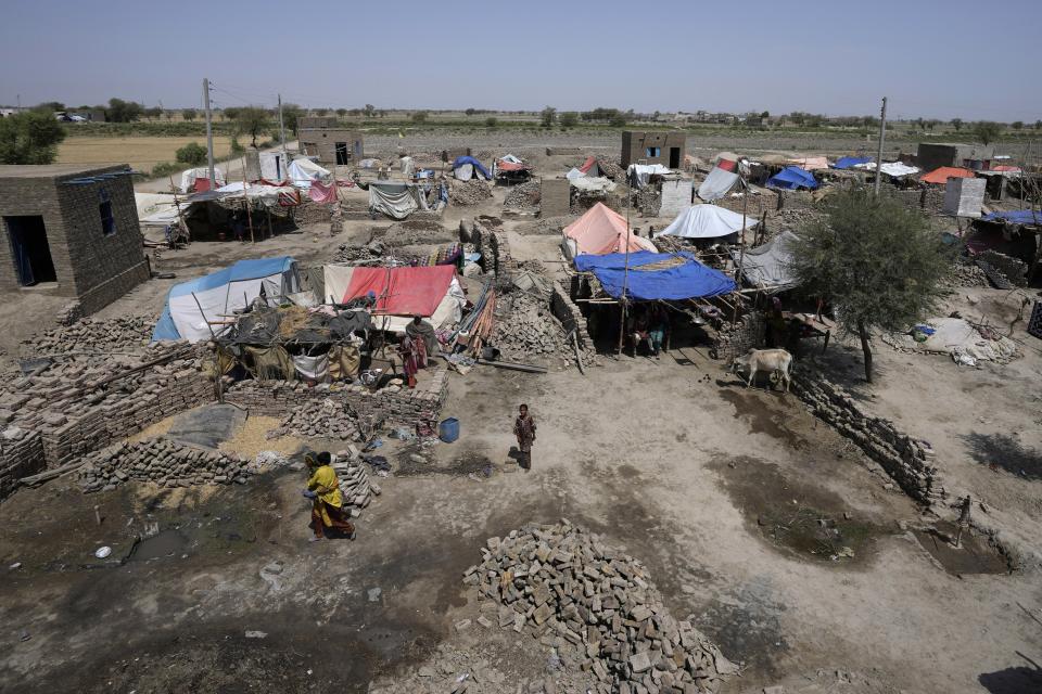 Women walk through their tents set up over the rubble of their damaged homes caused by last year's floods, at a village in Dada, a district of Pakistan's Sindh province, Wednesday, May 17, 2023. Many children are still without schools as authorities struggle to repair the extensive damage. A year on from the floods in Pakistan that killed at least 1,700 people, destroyed millions of homes, wiped out swathes of farmland, and caused billions of dollars in economic losses, the country still hasn't fully recovered. (AP Photo/Anjum Naveed)