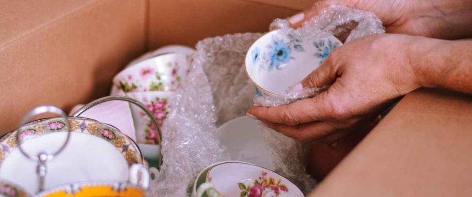 Woman packing a box with fine china dishes for moving